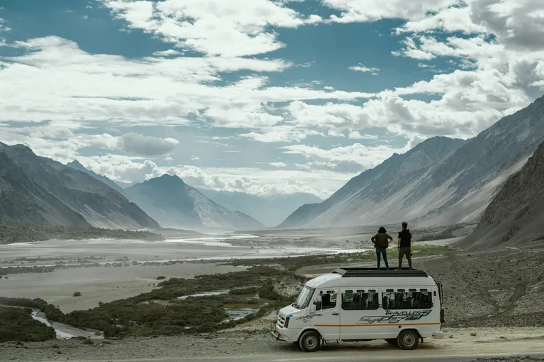 Travellers overlooking a Himalayan valley from their tour vehicle